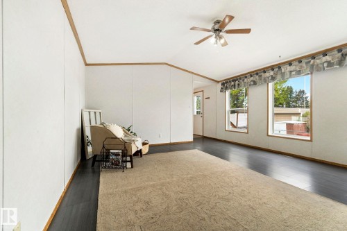 Spacious room featuring dark wood-finish flooring, white panel walls with wood trim, and a ceiling fan with integrated lighting - 49 Rim Road Nw, Edmonton, AB - Indoor Photo Showing Other Room