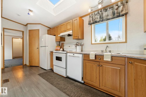 Kitchen featuring wood-finish flooring, light wood cabinetry, white appliances, a double basin sink, and a skylight - 49 Rim Road Nw, Edmonton, AB - Indoor Photo Showing Kitchen