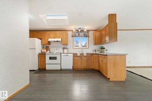 Kitchen featuring wood-finish cabinetry, white appliances, and a skylight - 49 Rim Road Nw, Edmonton, AB - Indoor Photo Showing Kitchen With Double Sink