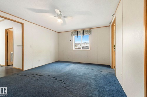 Carpeted room featuring a ceiling fan with integrated lighting, a window with a valance, and light-toned walls with wood trim - 49 Rim Road Nw, Edmonton, AB - Indoor Photo Showing Other Room