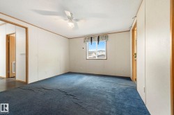 Carpeted room featuring a ceiling fan with integrated lighting, a window with a valance, and light-toned walls with wood trim - 
