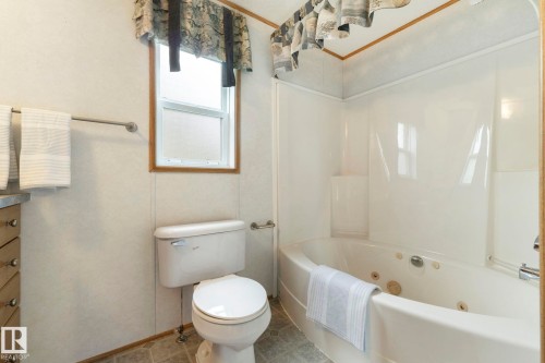 Bathroom featuring a white jetted tub, a white toilet, a window with wood trim, and a vanity with a countertop - 49 Rim Road Nw, Edmonton, AB - Indoor Photo Showing Bathroom