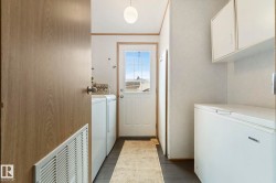 Mudroom area featuring a white paneled door with window panes, white upper cabinetry, and dark-finish flooring - 