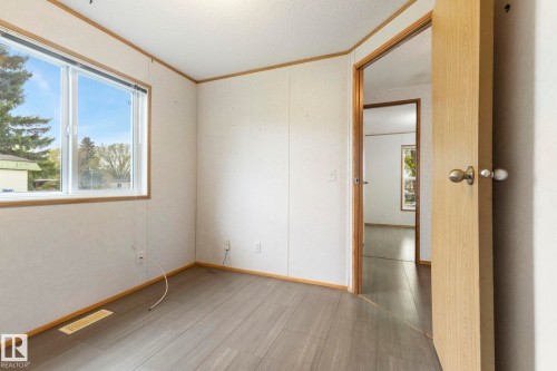 Interior room featuring wood-finish flooring, white panel walls, and a large window - 49 Rim Road Nw, Edmonton, AB - Indoor Photo Showing Other Room