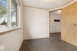 Room featuring wood-finish flooring, white panel walls, and a window with white trim - 