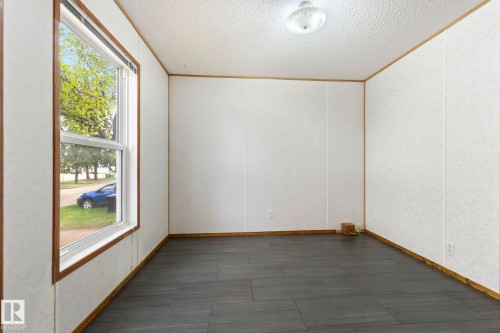 Spacious room featuring dark wood-finish flooring, white panel walls, and a large window with wood trim - 49 Rim Road Nw, Edmonton, AB - Indoor Photo Showing Other Room