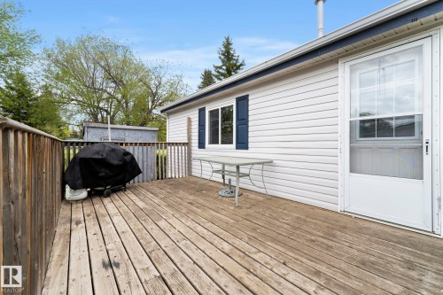 Expansive outdoor deck featuring wood flooring and railings, white vinyl siding, and a white screen door - 49 Rim Road Nw, Edmonton, AB - Outdoor With Deck Patio Veranda With Exterior