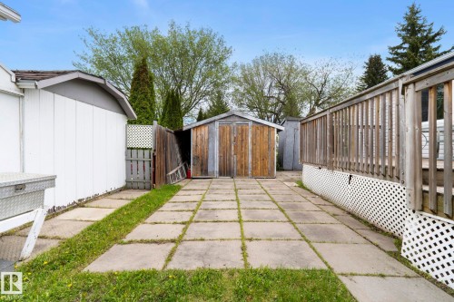 Paved patio area featuring concrete stepping stones, a wooden storage shed, and a wooden privacy fence - 49 Rim Road Nw, Edmonton, AB - Outdoor With Exterior