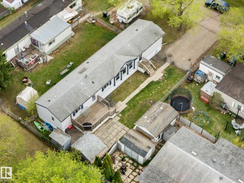 Spacious property featuring a large backyard with a wooden deck, mature trees, and a paved patio area - 49 Rim Road Nw, Edmonton, AB - Outdoor With View