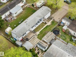 Spacious property featuring a large backyard with a wooden deck, mature trees, and a paved patio area - 