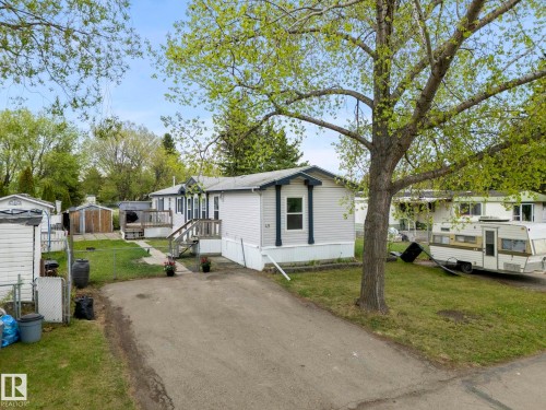 Exterior featuring light-colored siding, a dark trim, a front deck with steps, and a paved driveway - 49 Rim Road Nw, Edmonton, AB - Outdoor