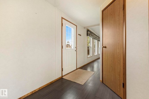 Entryway featuring dark wood-finish flooring, a paneled door with glass inserts, and a series of windows along the far wall - 49 Rim Road Nw, Edmonton, AB - Indoor Photo Showing Other Room