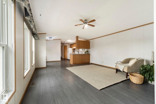 Spacious living area featuring wood-finish flooring, multiple large windows providing abundant natural light, and a ceiling fan - 49 Rim Road Nw, Edmonton, AB - Indoor Photo Showing Other Room