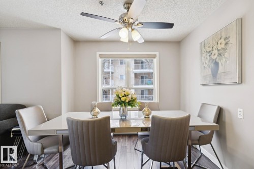 The dining area features a modern ceiling fan with lighting, a window with a view, and hardwood flooring - 202 17511 98A Avenue, Edmonton, AB - Indoor Photo Showing Dining Room