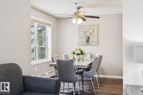 The dining area features hardwood floors, a large window, a ceiling fan with light, and light-colored walls - 202 17511 98A Avenue, Edmonton, AB - Indoor Photo Showing Dining Room