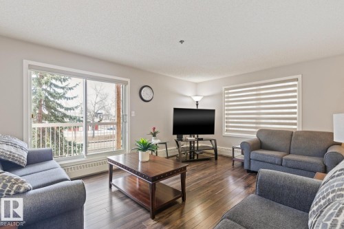 Living area featuring hardwood flooring and a sliding glass door leading to a balcony - 202 17511 98A Avenue, Edmonton, AB - Indoor Photo Showing Living Room
