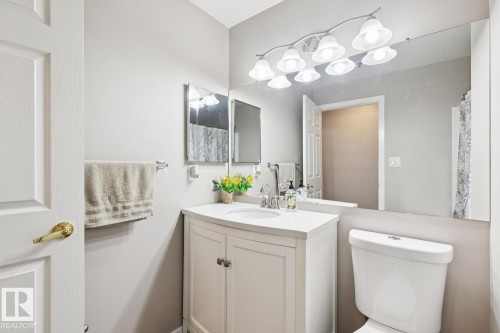 Bathroom featuring a white vanity with a countertop sink, a large wall mirror, and a contemporary light fixture - 202 17511 98A Avenue, Edmonton, AB - Indoor Photo Showing Bathroom