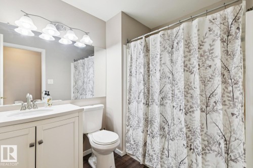 The bathroom features a vanity with a white countertop and a mirror with overhead lighting - 202 17511 98A Avenue, Edmonton, AB - Indoor Photo Showing Bathroom