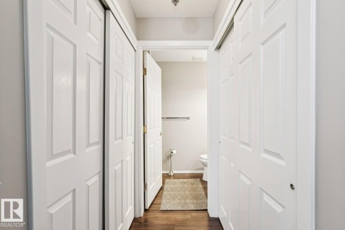 Hallway featuring white bi-fold doors, a wood-style floor, and light-colored walls - 202 17511 98A Avenue, Edmonton, AB - Indoor Photo Showing Other Room
