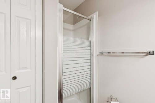 The property includes a shower with frosted glass doors, white paneled doors, and a chrome towel bar - 202 17511 98A Avenue, Edmonton, AB - Indoor