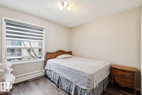 Room featuring a window with privacy blinds, dark wood flooring, and light-colored walls - 202 17511 98A Avenue, Edmonton, AB - Indoor Photo Showing Bedroom