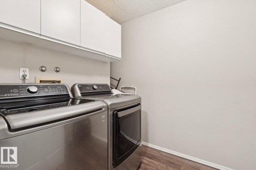 Laundry area featuring white cabinetry, a light-colored wall, and wood-look flooring - 202 17511 98A Avenue, Edmonton, AB - Indoor Photo Showing Laundry Room