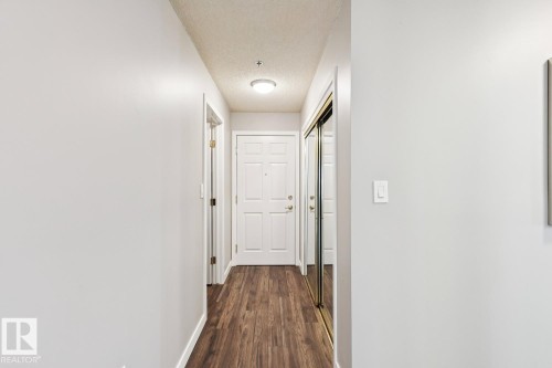 Entryway featuring wood-style flooring, a white paneled door, and a mirrored closet door - 202 17511 98A Avenue, Edmonton, AB - Indoor Photo Showing Other Room