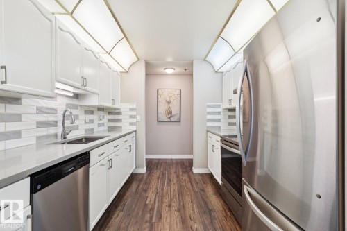 The kitchen features white cabinetry, stainless steel appliances, and wood-look flooring - 202 17511 98A Avenue, Edmonton, AB - Indoor Photo Showing Kitchen With Stainless Steel Kitchen With Double Sink With Upgraded Kitchen