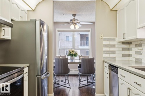 Kitchen featuring white cabinetry, stainless steel appliances, a tiled backsplash, and light-colored countertops - 202 17511 98A Avenue, Edmonton, AB - Indoor Photo Showing Kitchen