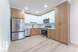 Modern kitchen featuring two-tone cabinetry, stainless steel appliances, recessed lighting, and wood-finish flooring - 