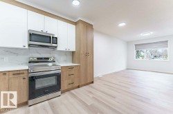 Modern kitchen featuring two-tone cabinetry with white upper and wood-finish lower cabinets, stainless steel appliances, and marble-look backsplash - 