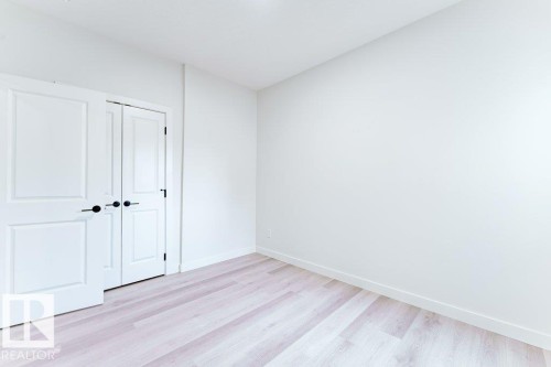 Light-toned wood-finish flooring complements the neutral wall color - 6920/6922 106 Street, Edmonton, AB - Indoor Photo Showing Other Room