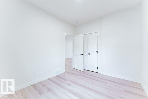 Bright interior space featuring light wood-finish flooring, white baseboards, and a white wall finish - 6920/6922 106 Street, Edmonton, AB - Indoor Photo Showing Other Room