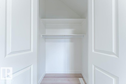 Closet with two paneled bifold doors, integrated shelving, and a hanging rod, all finished in white - 6920/6922 106 Street, Edmonton, AB - Indoor