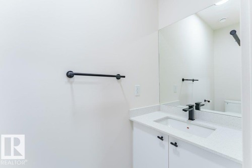 White vanity with a speckled countertop, integrated rectangular sink, and matte black faucet - 6920/6922 106 Street, Edmonton, AB - Indoor Photo Showing Bathroom