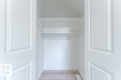 Closet with two paneled bifold doors, integrated shelving, and a hanging rod, all finished in white - 
