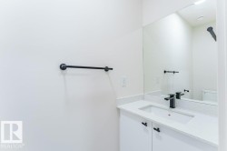 White vanity with a speckled countertop, integrated rectangular sink, and matte black faucet - 