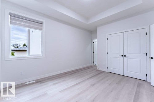 Bright room featuring light wood-finish flooring, white walls, and a tray ceiling - 6920/6922 106 Street, Edmonton, AB - Indoor Photo Showing Other Room