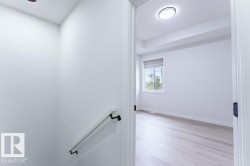 Bright room featuring wood-finish flooring, a window with roller blinds, and a tray ceiling - 