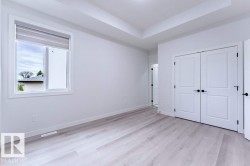 Bright room featuring light wood-finish flooring, white walls, and a tray ceiling - 