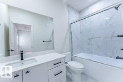 Contemporary bathroom featuring a white vanity with a rectangular undermount sink, a matte black faucet, and matching hardware - 