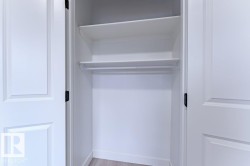 White bi-fold doors reveal a closet interior featuring two upper shelves and a clothing rod - 