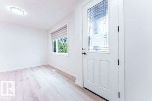 Entryway featuring a decorative glass panel door, light wood-finish flooring, a contemporary flush-mount ceiling light, and a window with a roller shade - 6920/6922 106 Street, Edmonton, AB - Indoor Photo Showing Other Room