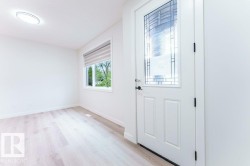 Entryway featuring a decorative glass panel door, light wood-finish flooring, a contemporary flush-mount ceiling light, and a window with a roller shade - 