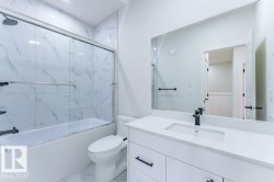Contemporary bathroom featuring a white vanity with a quartz countertop, integrated sink, and matte black faucet - 