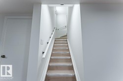 Staircase with wood-finish treads, light-toned risers, and a white wall-mounted handrail with dark brackets - 