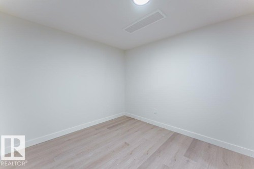 Neutral-toned interior room featuring wood-finish flooring, white walls, and white baseboards - 6920/6922 106 Street, Edmonton, AB - Indoor Photo Showing Other Room