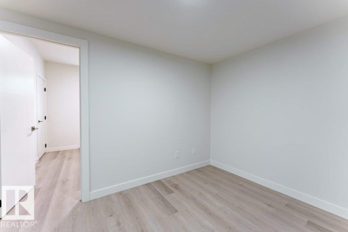 Bright interior space featuring light wood-finish flooring, white walls, and a white baseboard trim - 6920/6922 106 Street, Edmonton, AB - Indoor Photo Showing Other Room