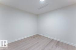 Neutral-toned interior room featuring wood-finish flooring, white walls, and white baseboards - 
