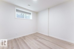 Light-filled room featuring a single window with a window well, light wood-finish flooring, white walls, white baseboards, and a flush-mount ceiling light - 